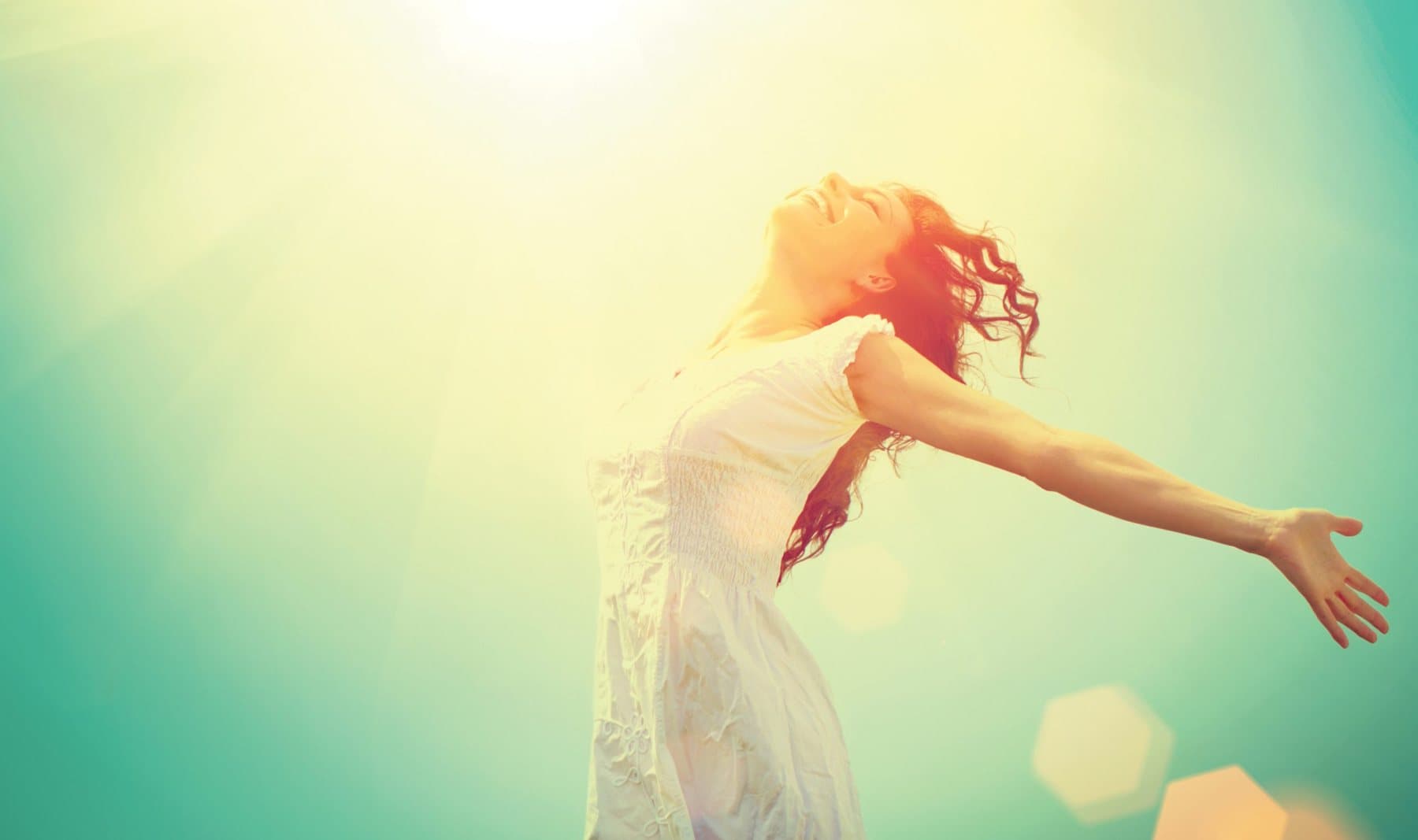 Woman with arms open in warm sunlight, reflecting the sense of freedom trauma therapy can help rebuild